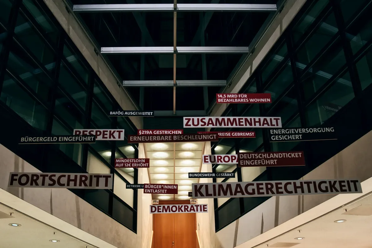 An architectural interior in Berlin featuring suspended German words and phrases highlighting social themes.