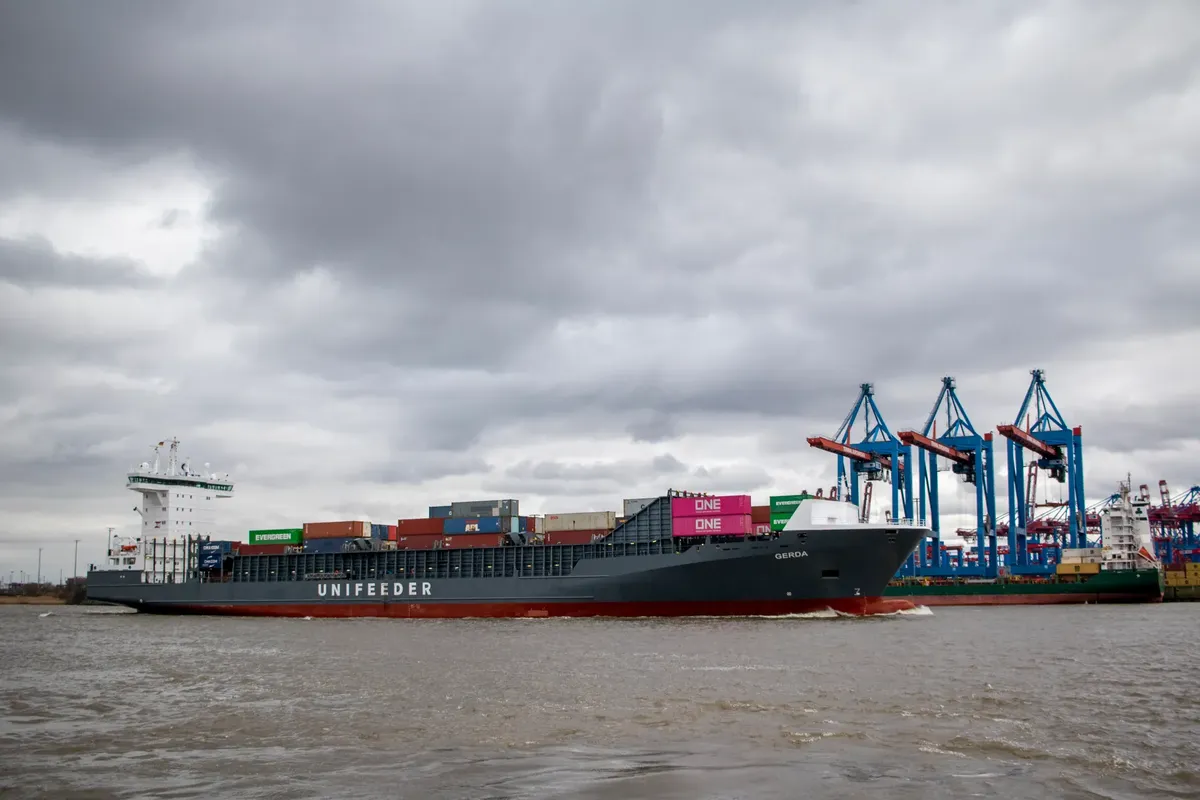 Unifeeder cargo ship at the Port of Hamburg on a cloudy day with visible cranes.